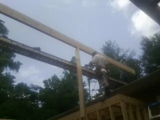 Carpenter setting a ridge beam over a new addition frame in Saint Helena Island