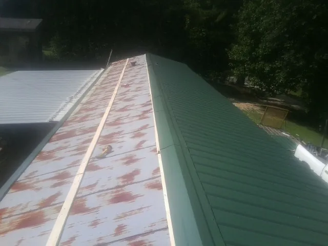 Old rusted panels beside newly installed green metal roofing — Wind Damage Roof Repair by Roofing Brothers in Saint Helena Island