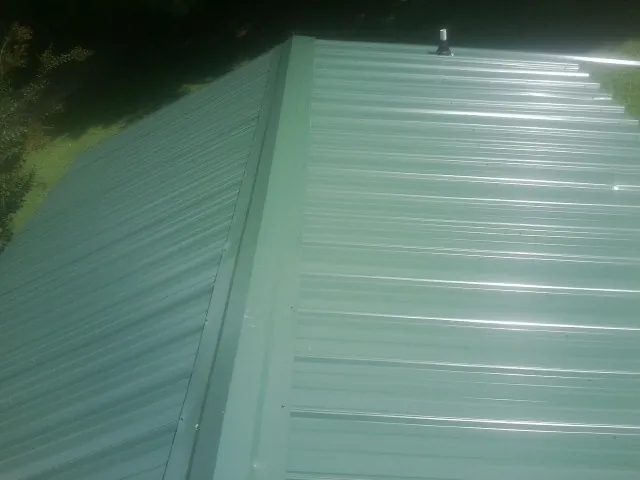 New green metal panels meeting at the ridge of a roof — Flat Roof Repair work by our crew in Saint Helena Island