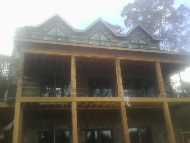 Dormers and porch framing on a large log home under construction — Roof Coating work by our crew in Saint Helena Island