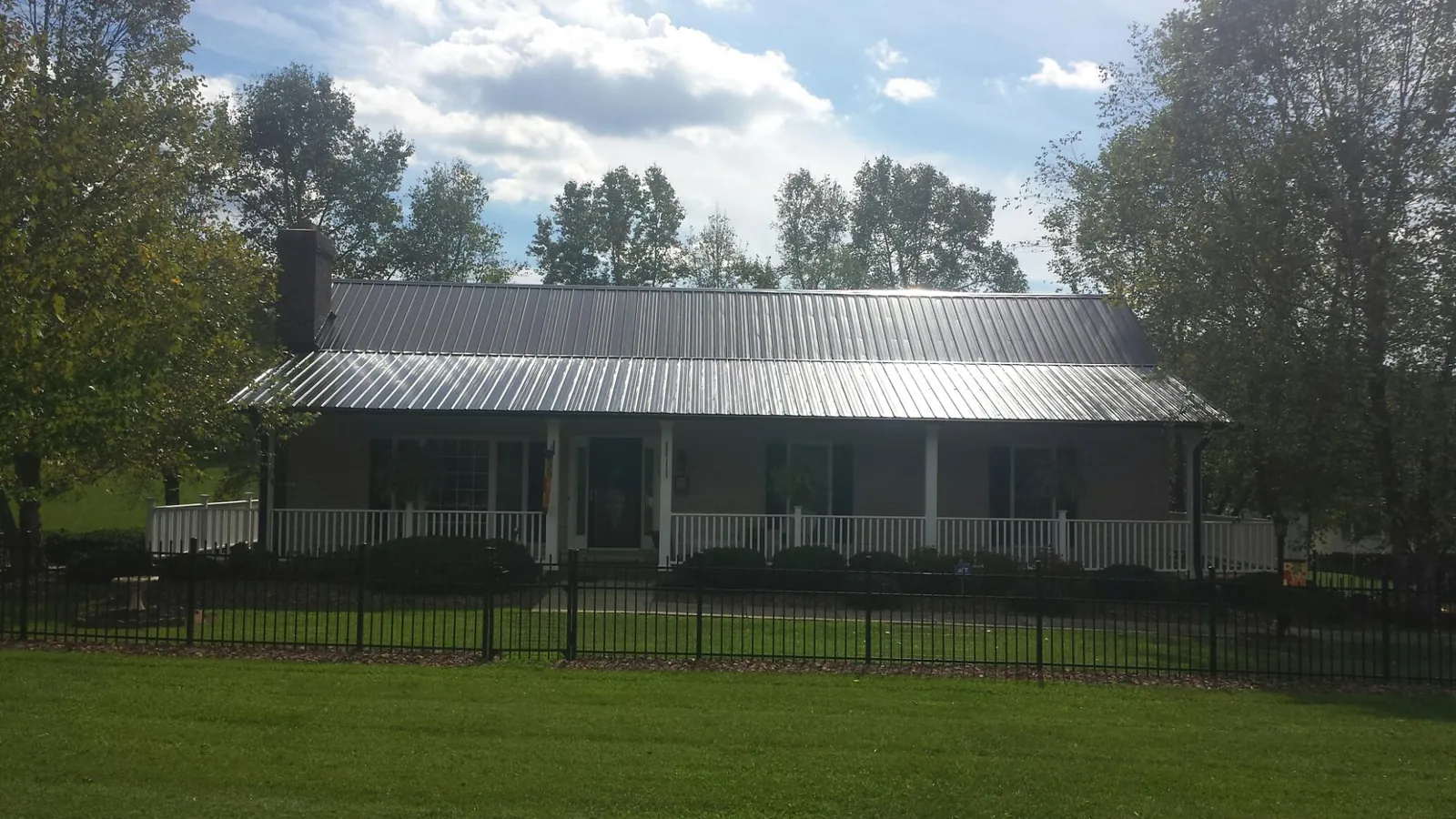 Gray metal roof on a brick ranch with a full width front porch — Gutter Guard Installation work by our crew in Saint Helena Island