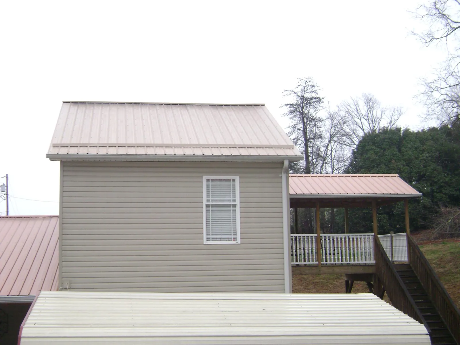 Tan metal roofs on a two story addition and attached porch, from a Roof Replacement job in Saint Helena Island