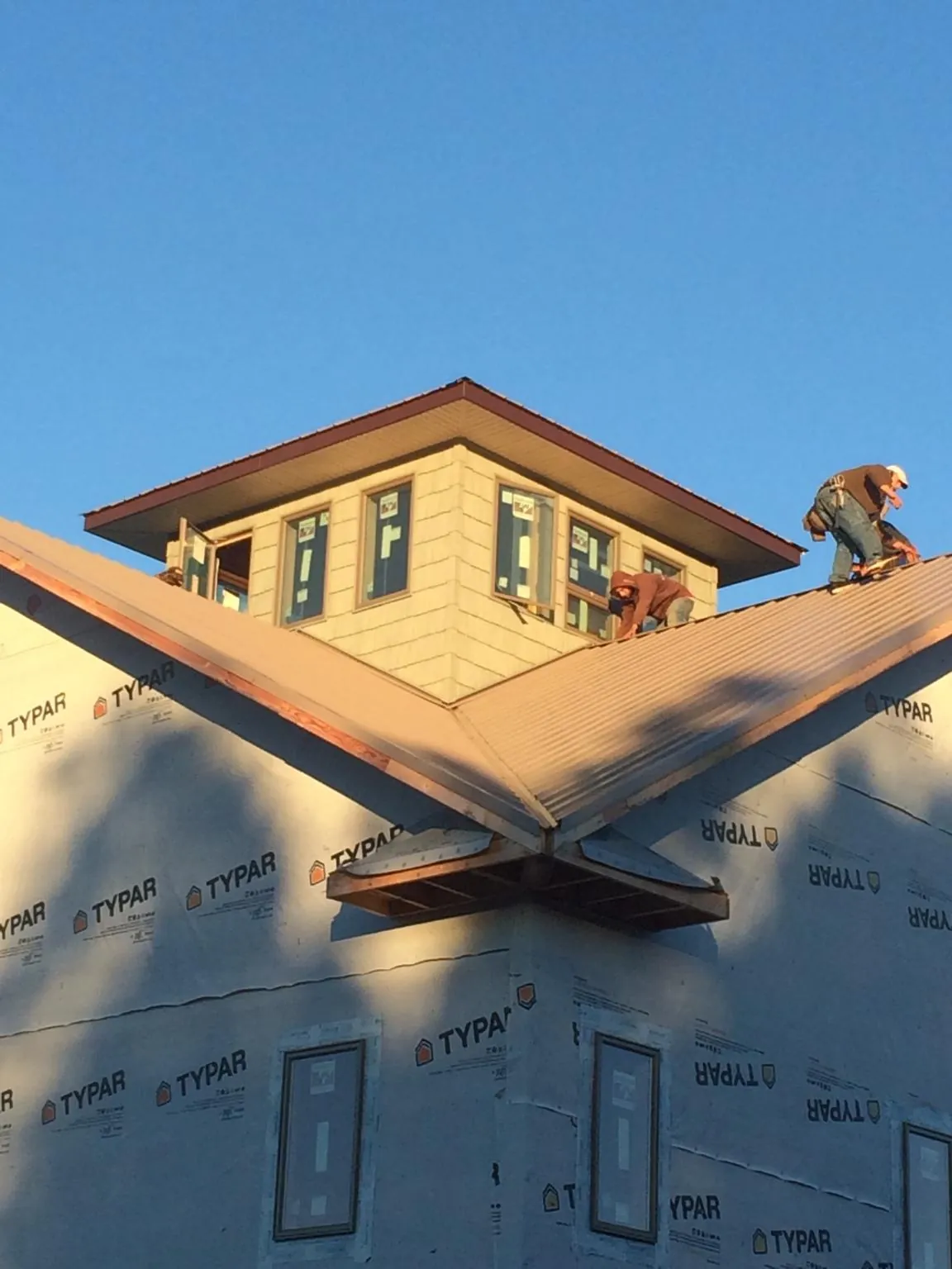 Roofers working around a rooftop cupola on a new metal roof at sunset — Roof Waterproofing in Saint Helena Island by Roofing Brothers
